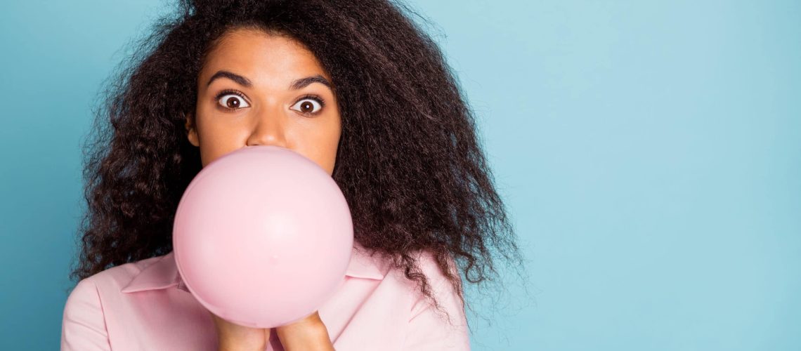 Closeup photo of pretty wavy dark skin lady holding hands big air balloon closing half crazy facial expression blowing wear pink shirt isolated blue color background